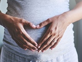 Week 18 pregnant woman holding her hands over her belly