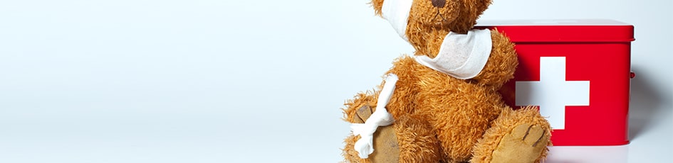 Bandaged teddy next to a first-aid box