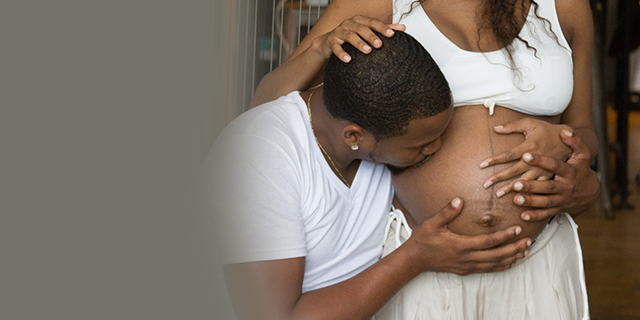 Dad-to-be kissing his pregnant partner's belly