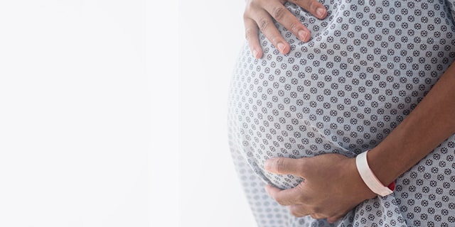 Week 37 pregnant woman in a hospital gown